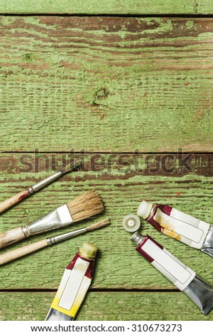 Paint brushes set and oil paint tubes on a green wooden background