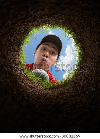 golfer blowing golf ball, view from inside the hole