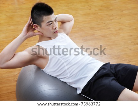 asian man doing sit up on fitness ball