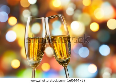 two glasses of champagne toasting against bokeh lights background