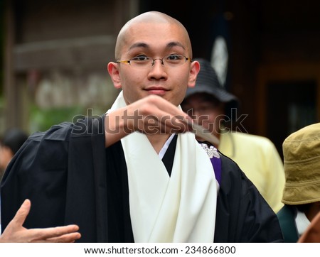 Koya, Japan - June 14, 2011: Young buddhist priest throwing good luck charms during Aoba festival, an annual event celebrating the birthday of Kobo Daishi, one of Japan's most renowned Buddhist saints