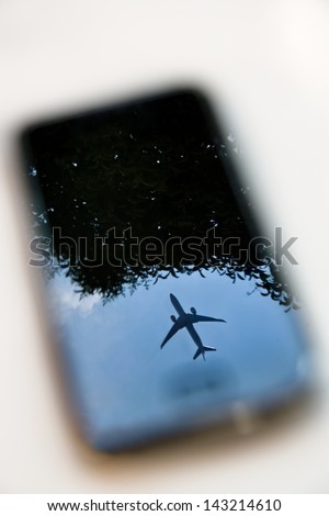 plane reflection on mobile phone with blue sky and tree