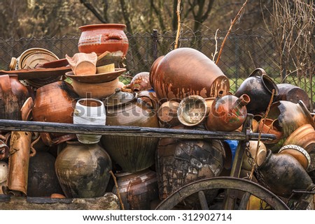 Damaged and cracked old handmade pottery vessels stacked and abandoned in a wooden cart