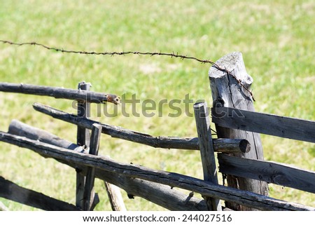 The old rickety fence with broken planks and barbed wire.
