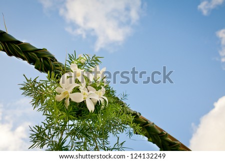 White Orchid arrangement on a wedding reception entrance ark made up of coconut leaves.