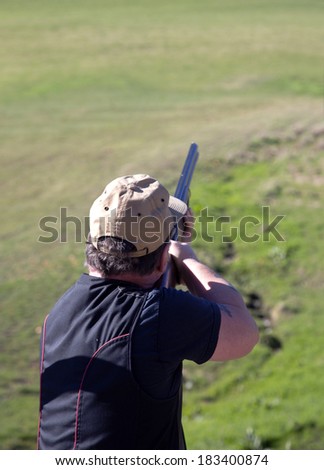 A clay shooter firing his gun at the clay pigeon disc