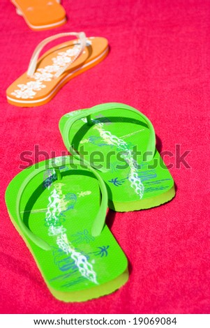 Two pairs of flip flops on red beachtowel. Symbol for a man and a woman on the beach.  Couple on vacation, fun, sea and summer concept. Space for copy.
