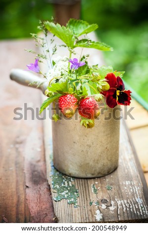 Bouquet of  strawberries in rustic cup on a wooden background
