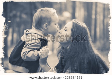 family mother with child son in park are playing black and white vintage card