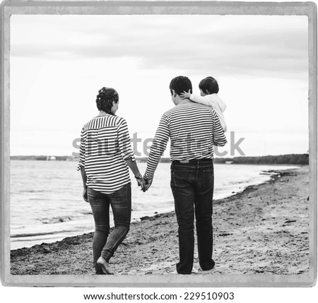 family on the beach father and mother with child in same clothes black and white