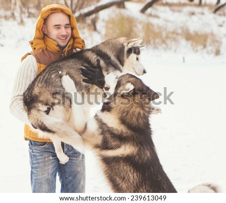 Man walking with dog winter time with snow in forest Malamute and Huskies friendship