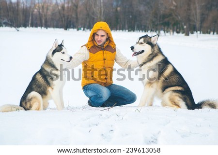 Man walking with dog winter time with snow in forest Malamute and Huskies friendship