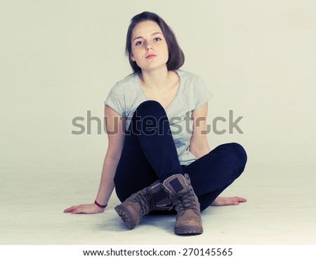 Cute woman young with freckle portrait in boots sitting on floor in studio