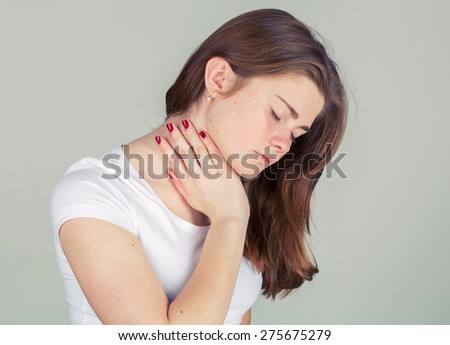 Woman with neck pain. Young woman holding her aching neck standing