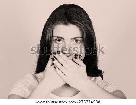 Surprised young woman covering mouth with hands and staring at camera emotion