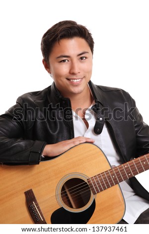 Young singer-songwriter sitting down with an acoustic guitar, wearing a white shirt and a black leather jacket. White background.