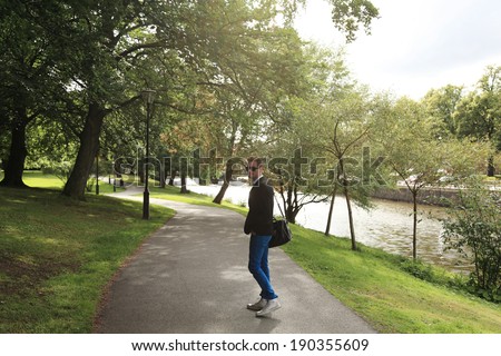 Relaxed young man taking a walk wearing a black jacket and black bag.
