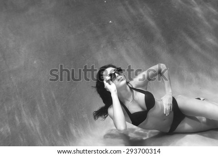 Sassy image of a woman swimming underwater in a bikini and sunglasses.