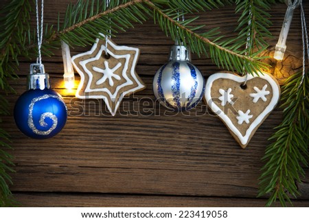 Christmas Balls, Ginger Breads and Fir Tree Branches with Fairy Lights on Wood with Copy Space