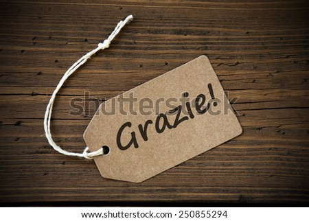 Close Up Of A Brown Label With White Ribbon On Wooden Background With Italian Text Grazie Frame And Vintage Or Retro Style