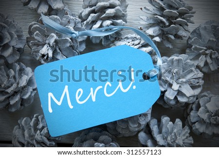 One Light Blue Label On Fir Cones And White Wooden Background. French Text Merci Means Thank You Vintage Or Retro Style Used As Winter Or Christmas Background With Frame
