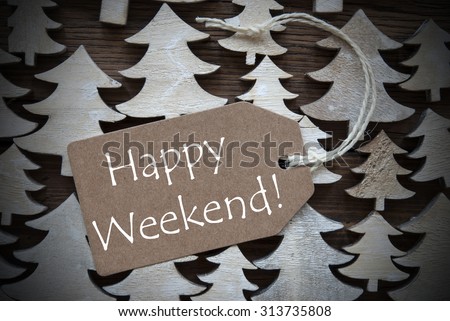 Brown Christmas Label With Ribbon On Wooden Christmas Trees Background. Vintage Style. Label With English Text Happy Weekend For Christmas Or Season Greetings.Close Up Or Macro