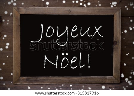 Brown Blackboard With French Text Joyeux Noel Means Merry Christmas As Greeting Card. Wooden Background. Vintage Rustic Style. Snowflakes Symbolizing Christmas Or Winter Season.