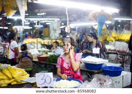 BANGKOK, THAILAND - MARCH 25: Seller using her smartphone at local market in Bangkok Chinatown on March 25, 2011 in Bangkok, Thailand. Bangkok  Chinatown is popular tourist attraction and a food haven