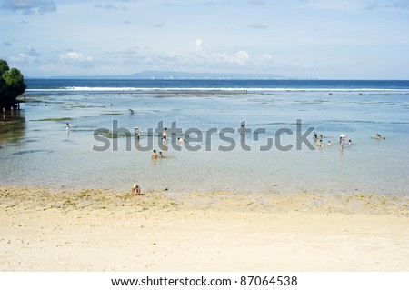 NUSA DUA,BALI, INDONESIA - APRIL 17: People swim in the ocean during tide ebb on April 17, 2011 in Nusa Dua,  Indonesia. Nusa Dua is known as enclave of large international 5-star resorts in Bali.