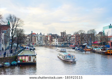 AMSTERDAM, NETHERLANDS - MARCH 17, 2014: Tourist boat cruises on canal  in Amsterdam. Almost 20 percent of all canal cruise boats are now electrically powered