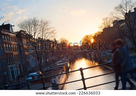 Couple walking on Amsterdam canal at sunset. Netherlands