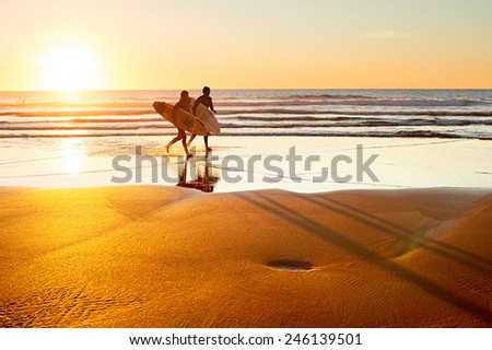 SAGRES, PORTUGAL - DEC 31, 2014: Two surfer running on the beach at sunset. Portugal has one of the best surfing scenes in Europe