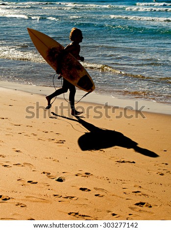 Surfer running on the beach towards the ocean. Portugal