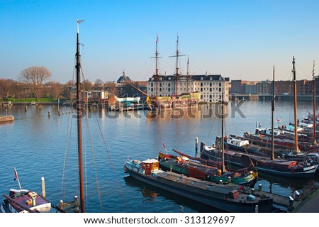 Row of houseboats on the Amstel river in Amsterdam, Netherlands. National Maritime Museum on the background