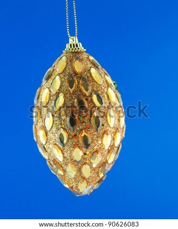 gold cone, Christmas decorations hanging on a golden thread against the blue background