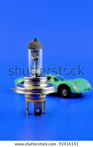 Car halogen bulb stands in the foreground and on the back of the car model