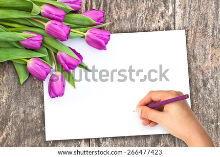 flowers on the oak gray table with white sheet of paper and hand