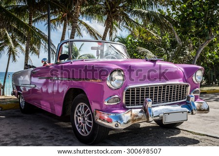 VARADERO, CUBA - JUNE 22, 2015: HDR pink american Oldtimer parked near the beach under palms