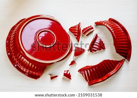 Shards of broken red kitchen utensils. Trying to glue pieces together is unsolvable task. Broken ceramic plate top view. Broken relationship, broken heart, family discord Photo stock © 