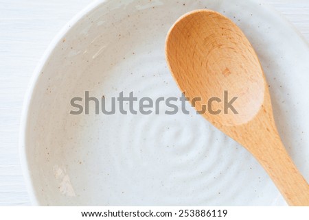 Wood spoon and white ceramic plate on white wood table