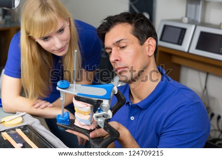 Two dental technicians looking at articulator in a dental lab