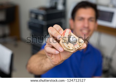 Dental technician presenting dental prosthesis in a dental lab