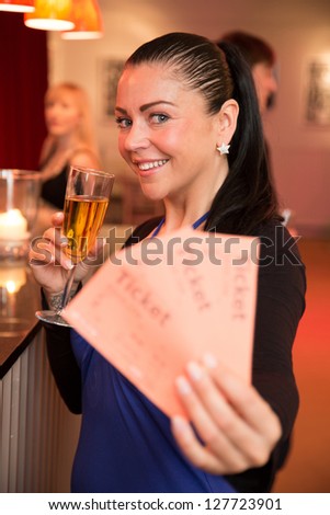 A beautiful woman in a theater, concert or cinema presenting tickets