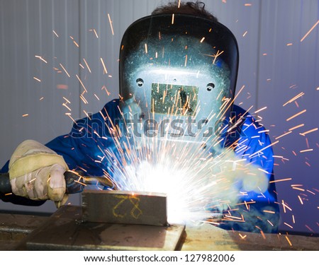 Man with welding helmet welding steel
