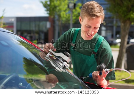 Glazier repairing windshield on a car after stone-chipping damage
