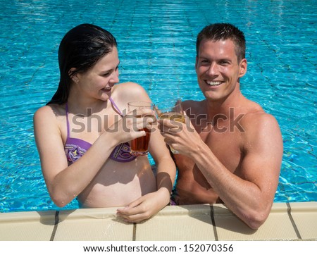 Couple drinking something in the sun at public swimming pool