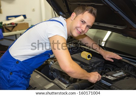 Mechanic with tools in garage or workshop repairing the motor of a car