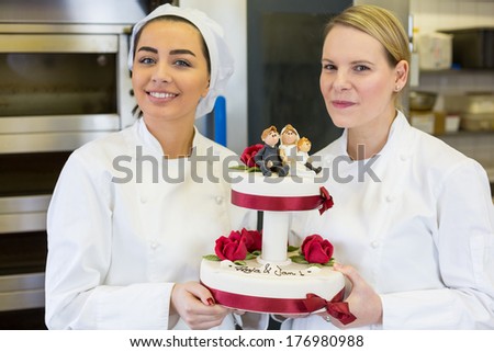 Confectioners or bakers presenting wedding cake in bakery