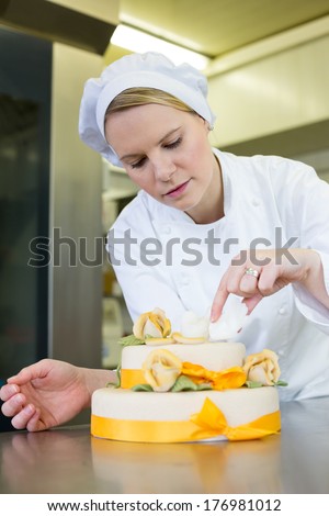 confectioner, baker or pastry cook preparing cake in bakery