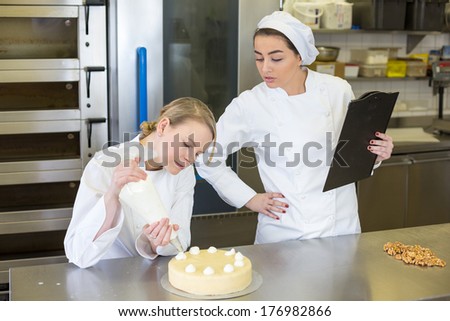 instructor in bakery teaching apprentice how to make cake